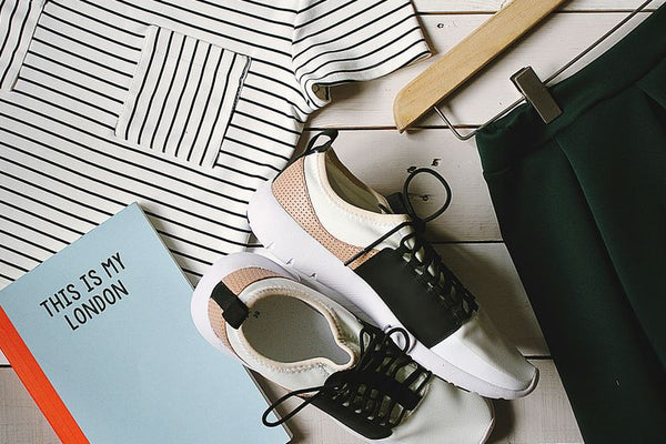 pair of white-and-black low-top sneakers near black skirt on brown clothes hanger top view photography