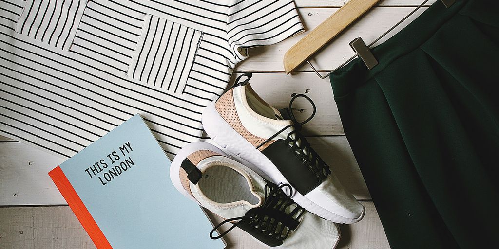 pair of white-and-black low-top sneakers near black skirt on brown clothes hanger top view photography